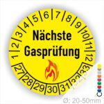 Prüfplaketten, Prüfetiketten rund, Farbe- Gelb, Text "Nächste Gasprüfung" in Schwarz danach eine Flamme als Pictogramm oder Icon in Rot, Startjahr- 27, Monatszahlen Oben und Jahreszahlen Unten in Kreisform. Über den Jahreszahlen.
