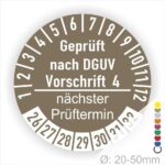 Prüfplakette mit Text Geprüft nach Dguv Vorschrift 4 und Nächster Prüftermin mit zwischen Strich in Weiss. Plaketten Farbe- Braun und Text in Weiss. Monatszahlen oben und Jahreszahlen unten beginnend mit Startjahr- 26