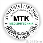 Prüfplakette MTK Medizintechnik rund, Farbe- Weiß, Text "Medizintechnische Kontrolle, MTK MEDIZINTECHNIK Nächster Prüftermin" in Schwarz. Startjahr- 26, Monatszahlen Oben und Jahreszahlen Unten in Kreisform. über den Jahreszahlen Text.