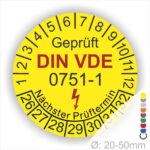 Prüfplaketten rund, Farbe- Gelb, Text "Geprüft gemäß DIN VDE 0751-1" in Schwarz danach ein Elektro- Pfeil in Rot, Startjahr- 26, Monatszahlen Oben und Jahreszahlen Unten in Kreisform. Über den Jahreszahlen Text "Nächster Prüftermin"