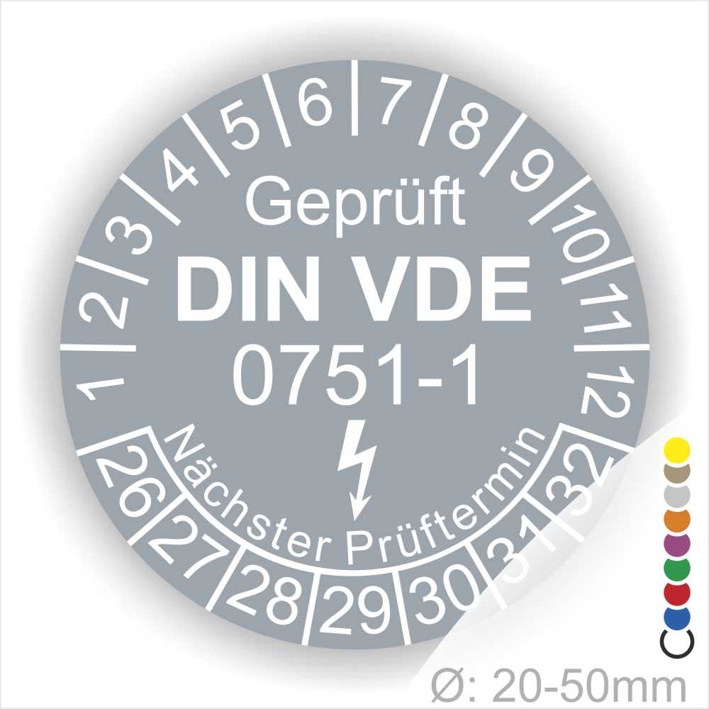 Prüfplaketten rund, Farbe- Grau, Text "Geprüft gemäß DIN VDE 0751-1" in Weiß danach ein Elektro- Pfeil in Weiß, Startjahr- 26, Monatszahlen Oben und Jahreszahlen Unten in Kreisform. Über den Jahreszahlen Text "Nächster Prüftermin"