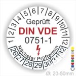 Prüfplaketten rund, Farbe- Weiß, Text "Geprüft gemäß DIN VDE 0751-1" in Schwarz danach ein Elektro- Pfeil in Rot, Startjahr- 26, Monatszahlen Oben und Jahreszahlen Unten in Kreisform. Über den Jahreszahlen Text "Nächster Prüftermin"