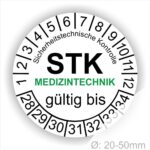 Prüfetiketten rund, Farbe- Weiß, Text "Sicherheitstechnische Kontrolle, STK MEDIZINTECHNIK gültig bis" in Schwarz. Startjahr- 28, Monatszahlen Oben und Jahreszahlen Unten in Kreisform. über den Jahreszahlen Text.