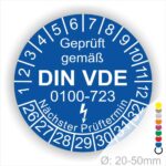 Prüfetiketten rund, Farbe- Blau, Text "Geprüft gemäß VDE 0100-0723" in Weiß danach ein Elektro- Pfeil in Weiß, Startjahr- 26, Monatszahlen Oben und Jahreszahlen Unten in Kreisform. Über den Jahreszahlen Text "Nächster Prüftermin"