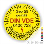 Prüfplakette, Prüfetikette rund, Farbe- Gelb, Text "Geprüft gemäß VDE 0100-723" in Schwarz danach ein Elektro- Pfeil in Rot, Startjahr- 26, Monatszahlen Oben und Jahreszahlen Unten in Kreisform. Über den Jahreszahlen Text "Nächster Prüftermin"