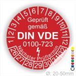Prüfetiketten rund, Farbe- Rot, Text "Geprüft gemäß VDE 0100-0723" in Weiß danach ein Elektro- Pfeil in Weiß, Startjahr- 26, Monatszahlen Oben und Jahreszahlen Unten in Kreisform. Über den Jahreszahlen Text "Nächster Prüftermin"