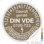 Prüfaufkleber rund, Farbe- Braun, Text "Geprüft gemäß VDE 0100-0723" in Weiß danach ein Elektro- Pfeil in Weiß, Startjahr- 27, Monatszahlen Oben und Jahreszahlen Unten in Kreisform. Über den Jahreszahlen Text "Nächster Prüftermin"