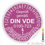 Prüfaufkleber rund, Farbe- Lila, Text "Geprüft gemäß VDE 0100-0723" in Weiß danach ein Elektro- Pfeil in Weiß, Startjahr- 27, Monatszahlen Oben und Jahreszahlen Unten in Kreisform. Über den Jahreszahlen Text "Nächster Prüftermin"