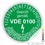 Prüfplaketten rund Farbe- Grün, Text "Geprüft gemäß VDE 0100" in Weiß danach ein Elektro- Pfeil in Weiß, Startjahr- 26, Monatszahlen Oben und Jahreszahlen Unten in Kreisform. Über den Jahreszahlen Text "Nächster Prüftermin"