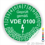 Prüfetikette rund, Farbe- Grün, Text "Geprüft gemäß VDE 0100" in Weiß danach ein Elektro- Pfeil in Weiß, Startjahr- 28, Monatszahlen Oben und Jahreszahlen Unten in Kreisform. Über den Jahreszahlen Text "Nächster Prüftermin"