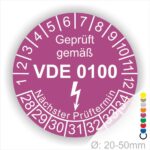 Prüfetikette rund, Farbe- Lila, Text "Geprüft gemäß VDE 0100" in Weiß danach ein Elektro- Pfeil in Weiß, Startjahr- 28, Monatszahlen Oben und Jahreszahlen Unten in Kreisform. Über den Jahreszahlen Text "Nächster Prüftermin"