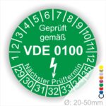 Prüfetikette rund, Farbe- Grün, Text "Geprüft gemäß VDE 0100" in Weiß danach ein Elektro- Pfeil in Weiß, Startjahr- 29, Monatszahlen Oben und Jahreszahlen Unten in Kreisform. Über den Jahreszahlen Text "Nächster Prüftermin"