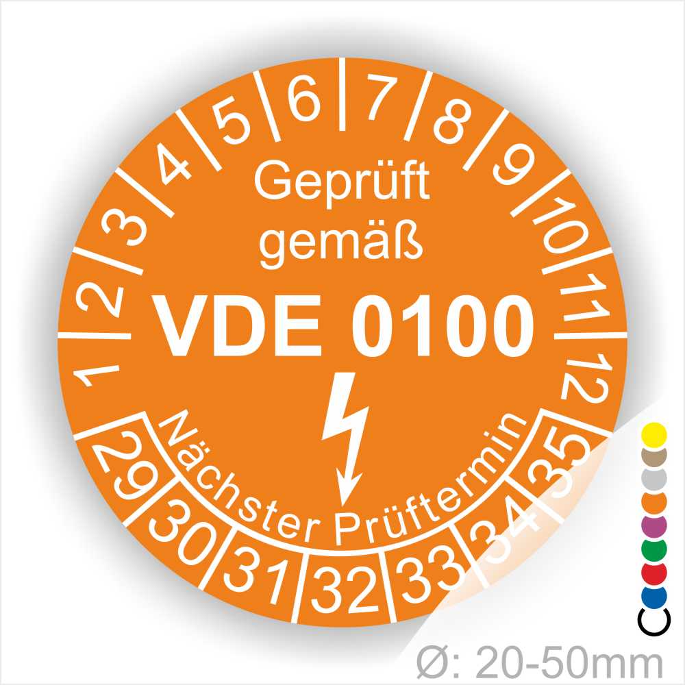 Prüfetikette rund, Farbe- Orange, Text "Geprüft gemäß VDE 0100" in Weiß danach ein Elektro- Pfeil in Weiß, Startjahr- 29, Monatszahlen Oben und Jahreszahlen Unten in Kreisform. Über den Jahreszahlen Text "Nächster Prüftermin"