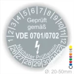 Prüfsiegel für elektrische Geräte gemäß VDE 0701/0702 mit einem Durchmesser von 20-50 mm, zeigt den nächsten Prüftermin und enthält eine Blitzsymbolik zur Kennzeichnung der Sicherheit.