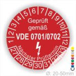 Rotes Prüfzeichen mit der Aufschrift "Geprüft gemäß VDE 0701/0702", das den nächsten Prüftermin anzeigt. Durchmesser: 20-50 mm. Ideal für die Kennzeichnung von elektrischen Geräten und Sicherheitsprüfungen.
