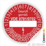 Rotes Prüfzeichen mit der Aufschrift „Geprüft gemäß VDE 0701/0702“. Das Label zeigt Platz für das Prüfdatum und den nächsten Prüftermin. Durchmesser zwischen 20-50 mm, geeignet für elektrische Geräte.