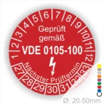 Rotes Prüfetikett mit der Aufschrift "Geprüft gemäß VDE 0105-100" und Angaben zum nächsten Prüftermin. Durchmesser zwischen 20 und 50 mm, geeignet für die Kennzeichnung von elektrischen Geräten.